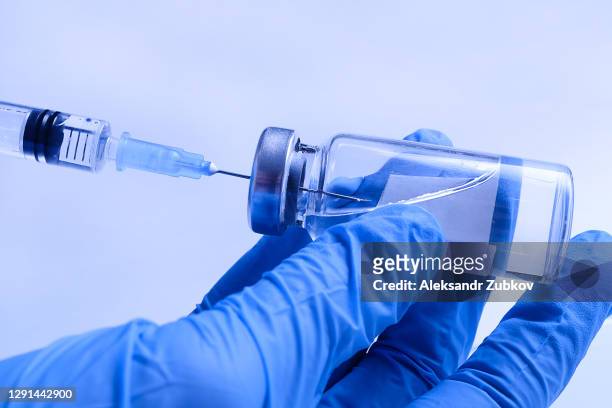 a doctor in medical protective gloves takes a medicine or vaccine from a glass ampoule into a syringe. concept of treatment and prevention of spread of covid-19 infection, virus and pneumonia. - injecteren stockfoto's en -beelden