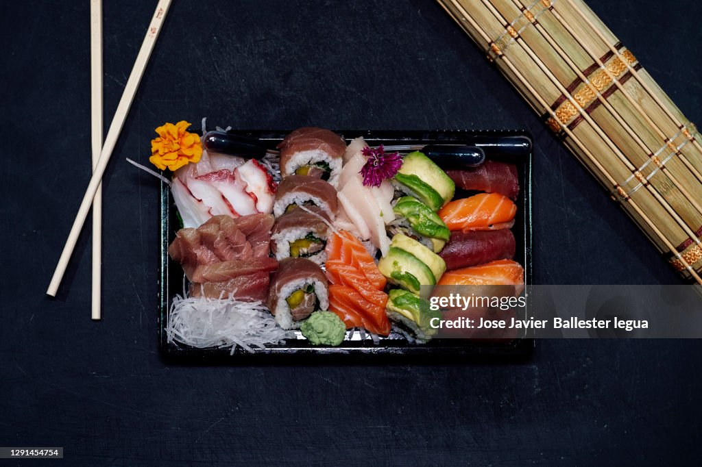 Close-up of a take-away tray with assorted sushi. Nigiri, Maki, Uramaki, Temaki, Oshi, Osomaki, Temari, Futomaki, Gunkan, Jazari, Oshi battera, Inari Dark food