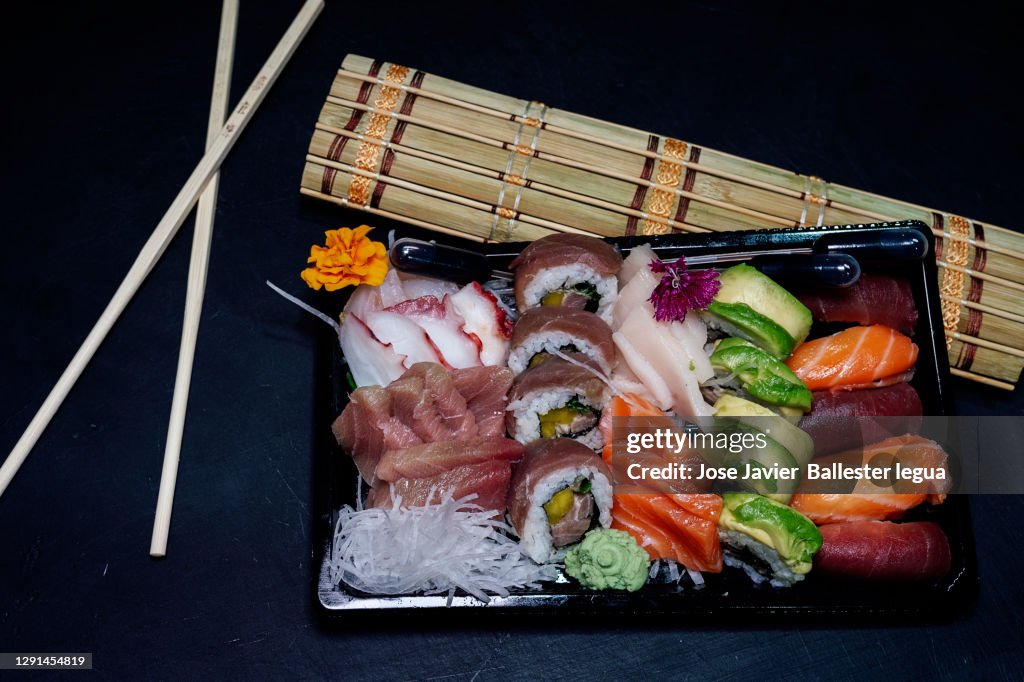 Close-up of a take-away tray with assorted sushi. Nigiri, Maki, Uramaki, Temaki, Oshi, Osomaki, Temari, Futomaki, Gunkan, Jazari, Oshi battera, Inari Dark food