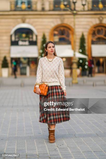 Maria Rosaria Rizzo wears a golden necklace, a white wool pullover with geometric printed patterns from L'Imprevu, a red checked pleated skirt from...