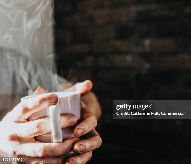 hands gripping a hot, steaming mug of coffee - tea hot drink stock-fotos und bilder