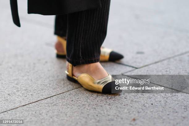 Alba Garavito Torre wears black pants, Chanel golden flat shoes with black tips, on December 10, 2020 in Paris, France.