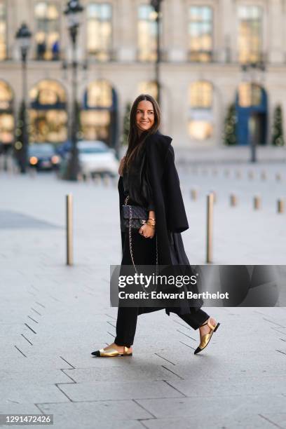 Alba Garavito Torre wears earrings, a black oversized leather top with puff sleeves from Munthe, a black wool long coat from Zara, a black leather...