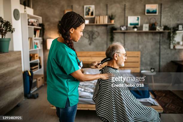nurse taking care of a nursing home senior user - lockdown haircut stock pictures, royalty-free photos & images