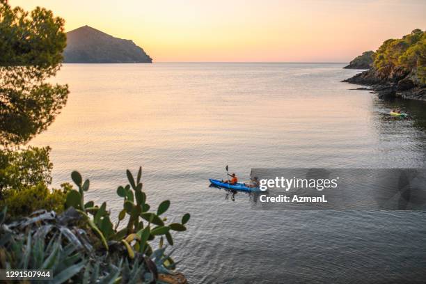 kayakers che remare lungo la costa mediterranea all'alba - kayaking foto e immagini stock