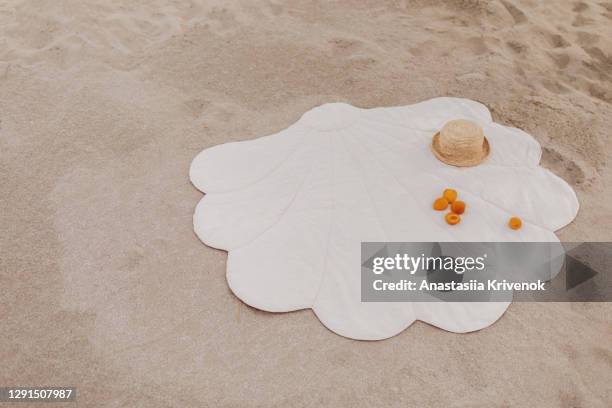 beautiful shell shape beach mat on sand with straw parasol. - beach towel stockfoto's en -beelden