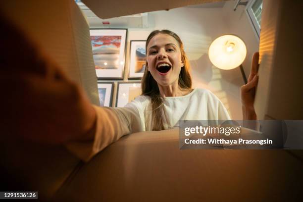 smiling woman opening a carton box - surprise portrait photos et images de collection