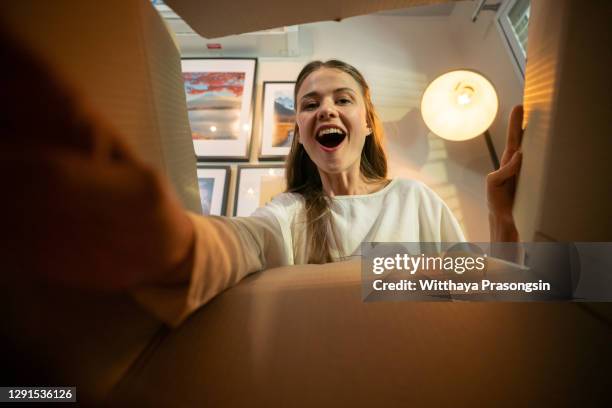 smiling woman opening a carton box - aprire foto e immagini stock