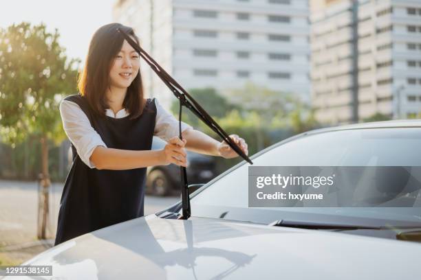jonge aziatische vrouw die ruitenwisser controleert - ruitenwisser auto stockfoto's en -beelden