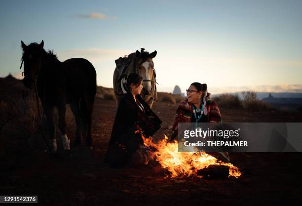 navajo sisters having fun around fire at sunset on monument valley - horseback riding arizona stock pictures, royalty-free photos & images