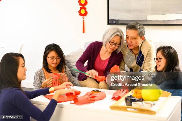 family celebrating chinese new years at home - 20 24 years asian stock pictures, royalty-free photos & images