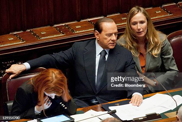 Michela Brambilla, Italy's tourism minister, left, looks at a tablet computer as Silvio Berlusconi, Italy's prime minister, center, speaks with...