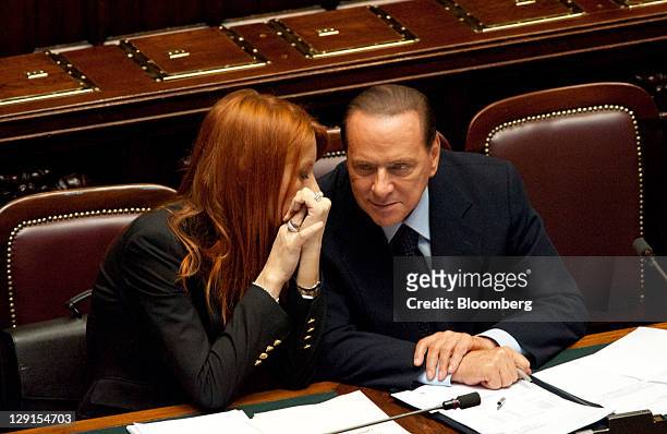 Michela Brambilla, Italy's tourism minister, left, speaks to Silvio Berlusconi, Italy's prime minister, during a parliamentary session inside the...