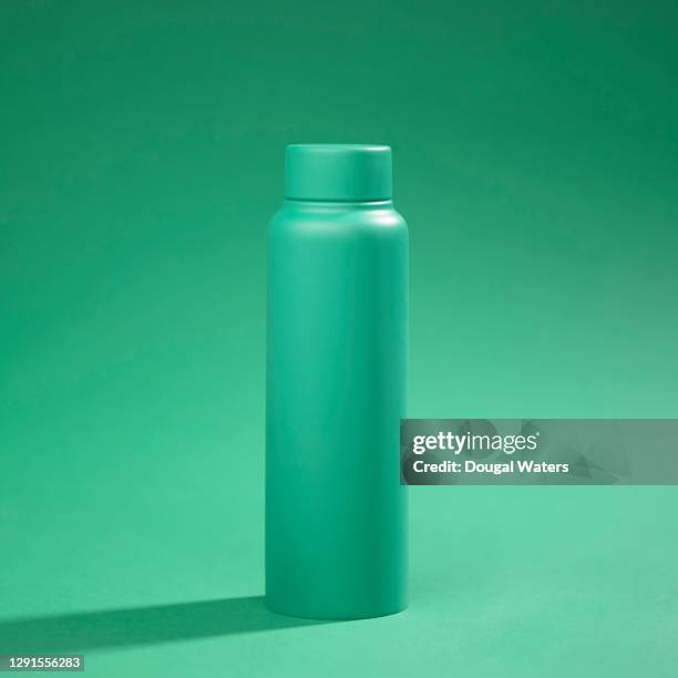 green reusable water bottle on green background. - insulated drink container stock pictures, royalty-free photos & images