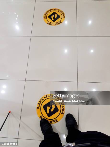 a man standing on the social distance safety sign on market floor during corona virus (covid-19) pandemic. - pov shoes stock-fotos und bilder