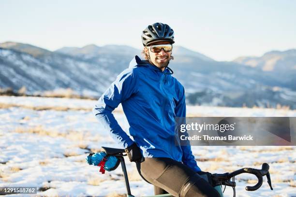 portrait of smiling male cyclist riding gravel bike on winter afternoon - giacca blu foto e immagini stock