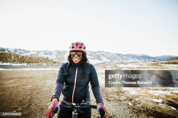 portrait of smiling female cyclist riding gravel bike at sunset on winter evening - bicycle safety light stockfoto's en -beelden