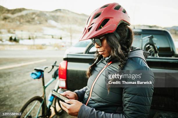 Female cyclist checking smart phone after riding gravel bike on winter evening