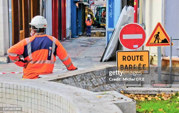 Chantier voirie dans une petite rue, panneaux route barrée et ouvrier de dos avec un casque blanc, 18 novembre 2020, Le Mans, France.