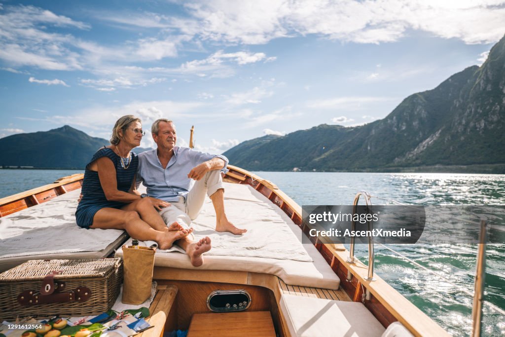 Pareja madura relajarse en velero moviéndose a través del lago Lugano