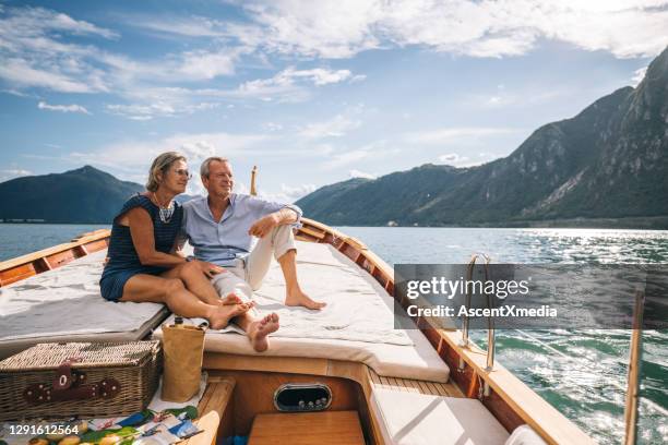 mature couple relax on sailboat moving through lake lugano - mulher sentada na cara do homem imagens e fotografias de stock