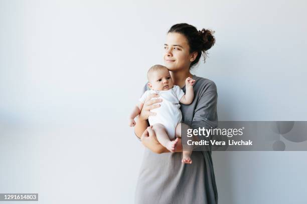 woman holding newborn baby and looking with love and care - baby background stockfoto's en -beelden