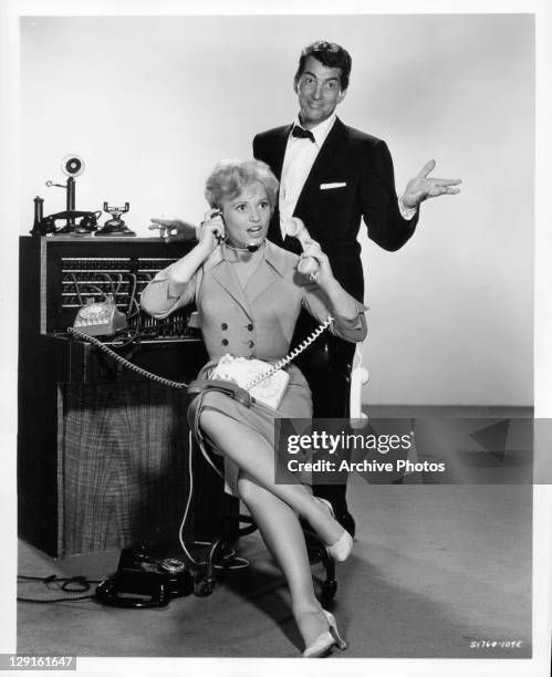 Judy Holliday manning the phones with Dean Martin behind her in a scene from the film 'Bells Are Ringing', 1960.