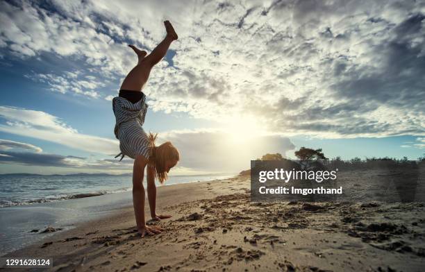 teenage girl doing handstand on the beach. - adrenaline stock pictures, royalty-free photos & images