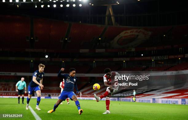 Bukayo Saka of Arsenal crosses the ball under pressure from Kyle Walker-Peters and Stuart Armstrong of Southampton during the Premier League match...