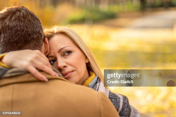 serious woman embracing her boyfriend. - suspicion infidelity stock pictures, royalty-free photos & images