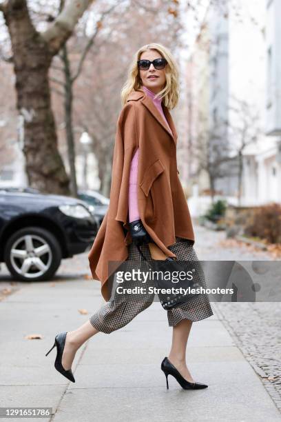 German TV host Tanja Buelter wearing sunglasses by Escada, black pumps by Buffalo, brown and black checkered pants by Marc Cain, a pink turtleneck...