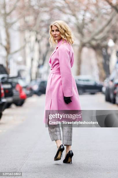 German TV host Tanja Buelter wearing black pumps by Buffalo, grey checkered pants by Marc Cain, a pink turtleneck pullover by Marc Cain, a long pink...