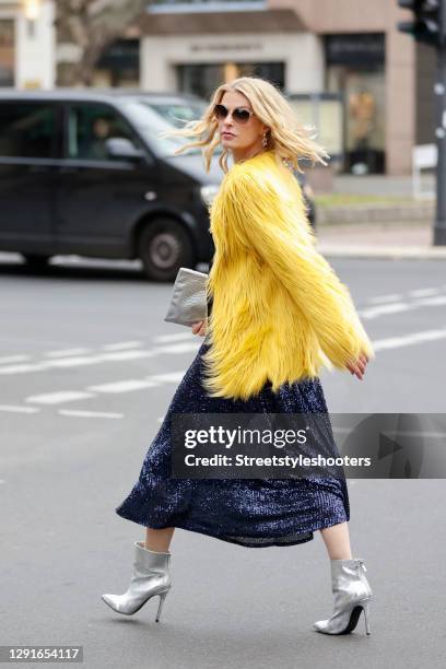 German TV host Tanja Buelter wearing silver vintage ankle booties, vintage silver star earrings, a midi legth dark blue sequin skirt by Riani, a...