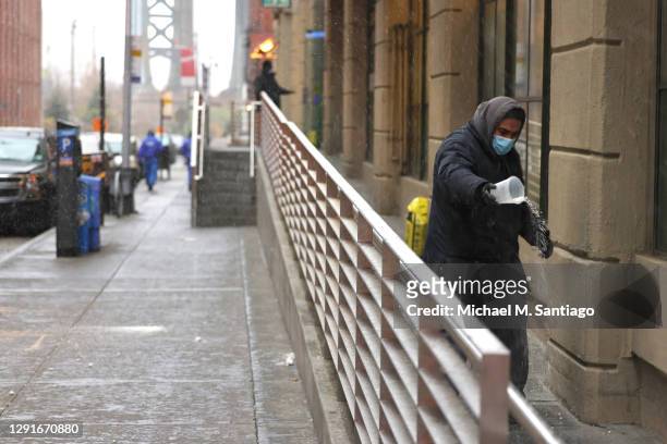 Man pours salt on a walkway in preparation for snow in the Dumbo neighborhood of Brooklyn on December 16, 2020 in New York City. New York City is...