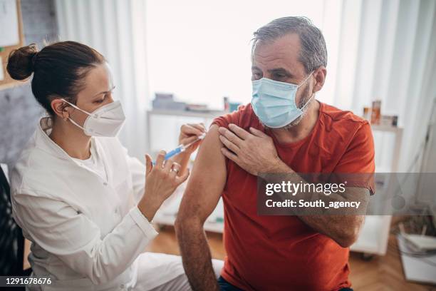 one man getting a coronavirus vaccine - man wearing protective face mask stock pictures, royalty-free photos & images