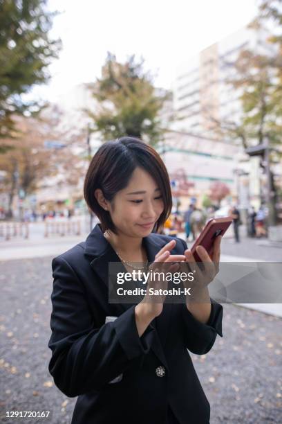 スーツを着た若い女性がスマートフォンでメッセージを入力する - 若い女性一人 ストックフォトと画像