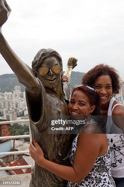 People pose with a bronze statue of Michael Jackson at a lookout point in favela Santa Marta in Rio de Janeiro, Brazil on October 9, 2011. The statue...