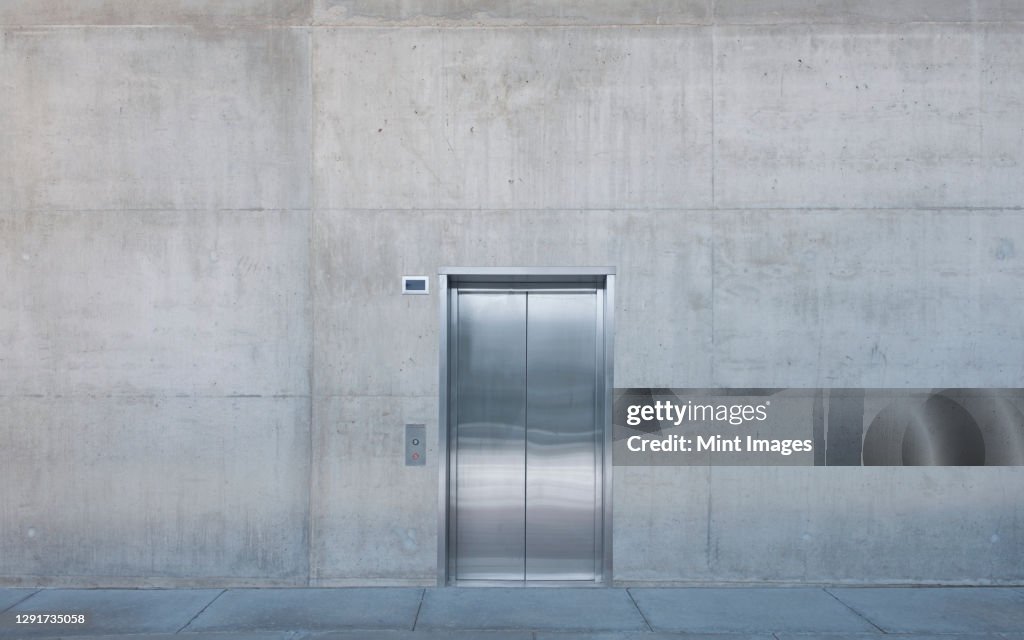 Metal elevator doors in a concrete wall.