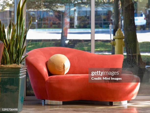 red chaise longue and potted plant in office or hotel lobby. - diva imagens e fotografias de stock