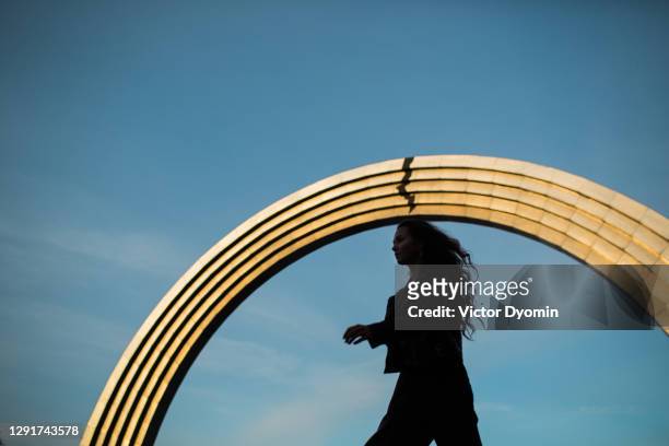 young woman walks under the shiny arch - autumn kyiv stock pictures, royalty-free photos & images