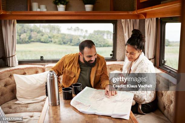 family reading map in motor home - family on couch with mugs stock-fotos und bilder