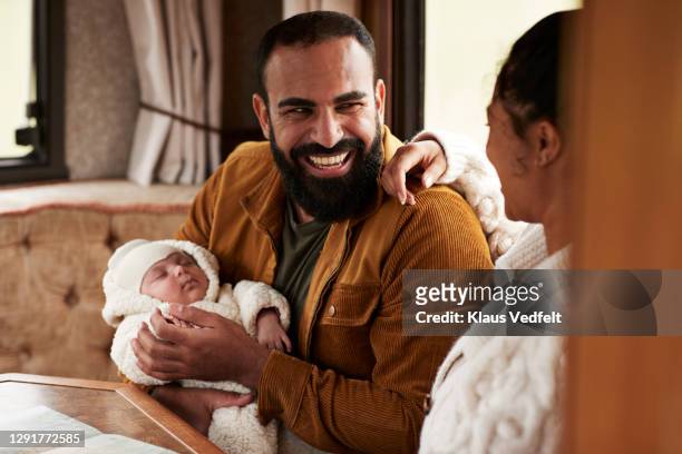 father laughing while carrying daughter and looking at mother in camper van - father newborn stock pictures, royalty-free photos & images