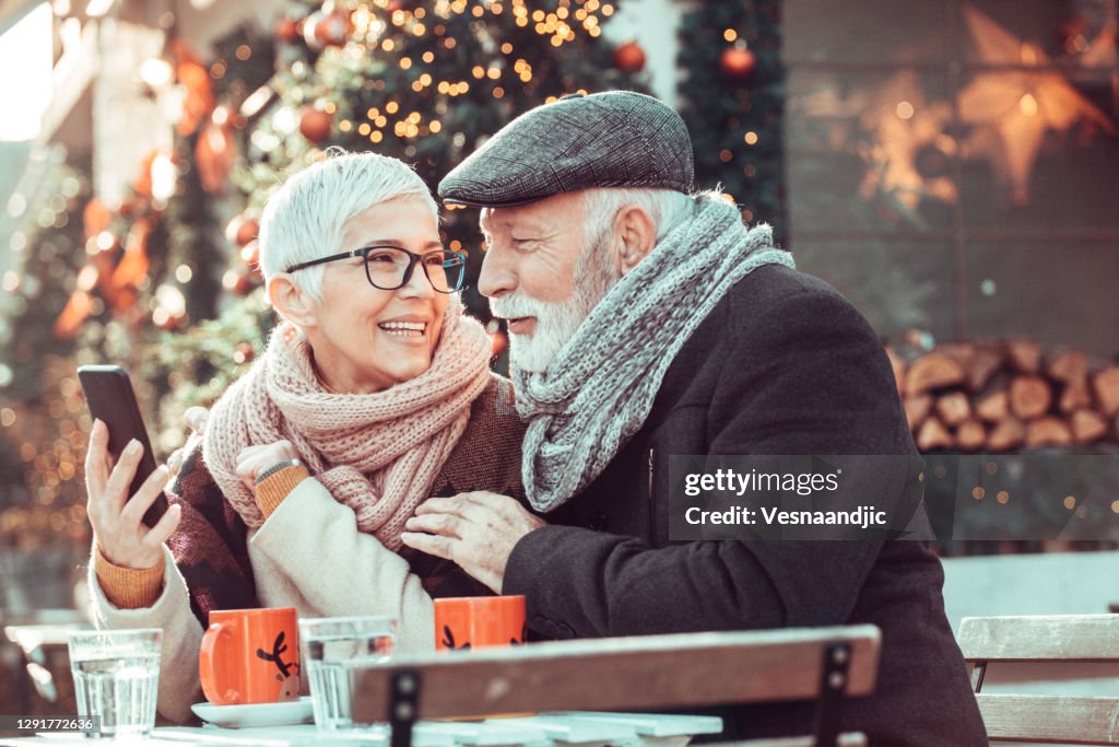 Senior couple during Christmas shopping, sit at sidewalk cafe for warming up