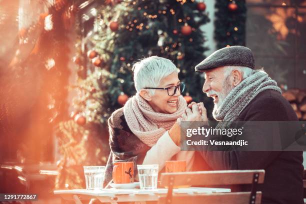 hoger paar tijdens het winkelen van kerstmis, zit bij stoepcafé voor het verwarmen - christmas city stockfoto's en -beelden