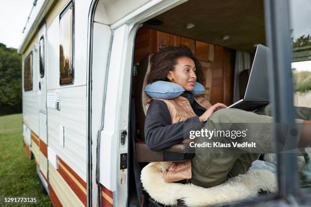 woman with neck pillow using laptop in motor van - work in progress stock-fotos und bilder