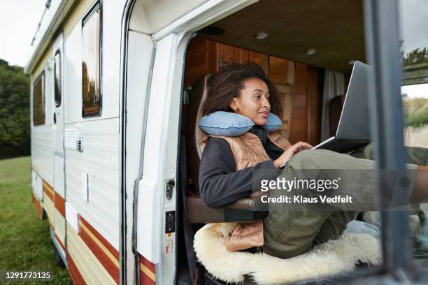 woman with neck pillow using laptop in motor van - telecommuting stock pictures, royalty-free photos & images