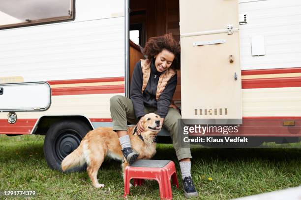 woman sitting with dog on doorway of camper van - camper van imagens e fotografias de stock