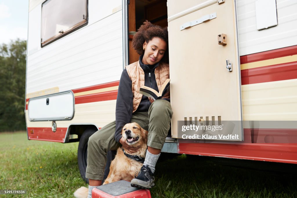 Woman with dog reading book in motor van