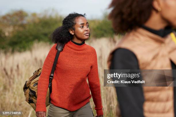 woman walking with friend in agricultural field - african american hiking stock-fotos und bilder