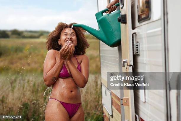woman having bath while man pouring water from can - woman shower bath stock-fotos und bilder